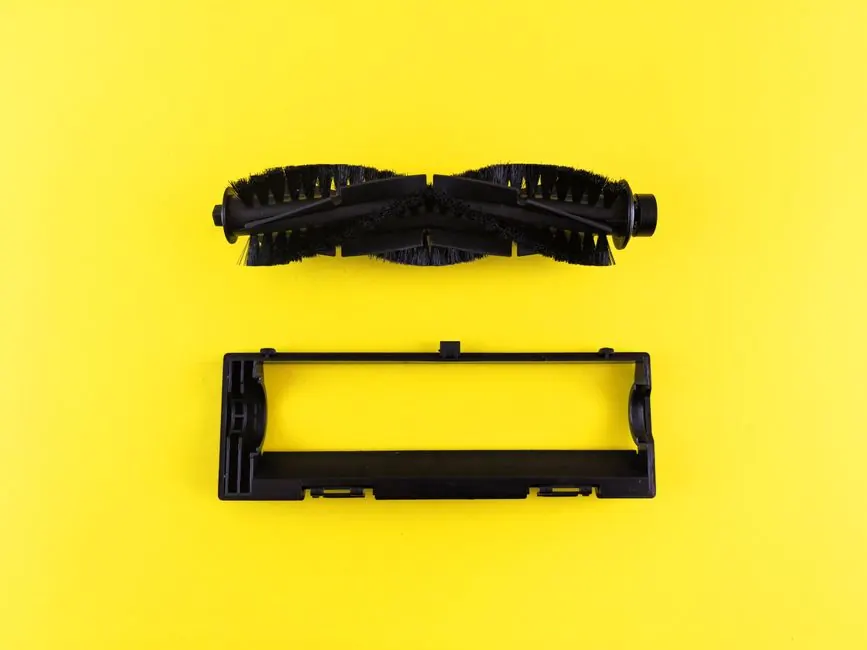 Close-up of vacuum cleaner components on vibrant yellow surface, highlighting maintenance and cleaning.