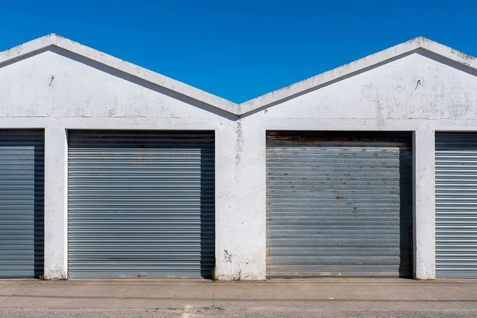 Image of industrial garage doors with corrugated metal under a clear blue sky, featuring a minimalist architectural style.